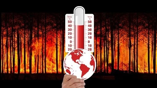 Eine Hand hält eine Erdkugel vor ein Thermometer. Im Hintergrund ein Waldbrand.